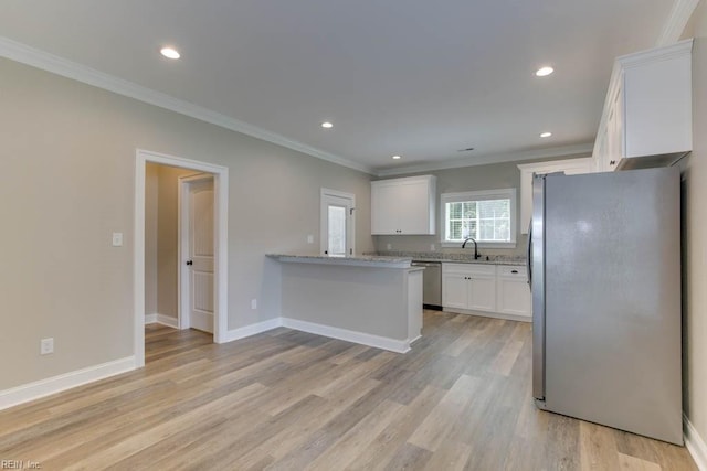 kitchen with light wood finished floors, a peninsula, appliances with stainless steel finishes, white cabinetry, and crown molding