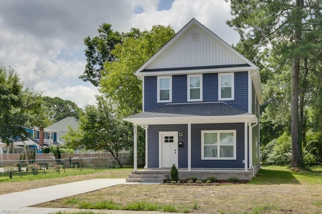 view of front of property with a porch, a shingled roof, a front yard, and fence