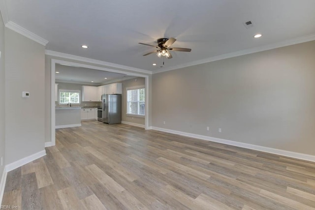 unfurnished living room featuring ceiling fan, crown molding, light wood-type flooring, and baseboards