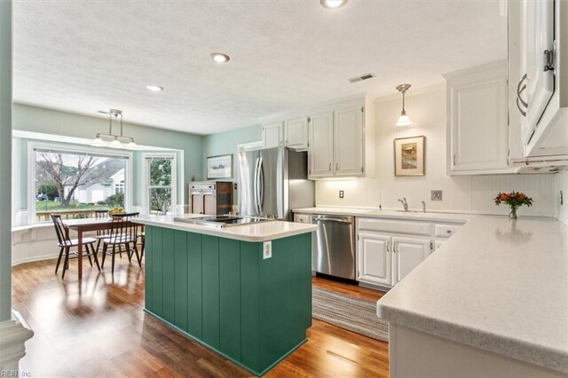 kitchen with visible vents, a kitchen island, light countertops, white cabinets, and appliances with stainless steel finishes