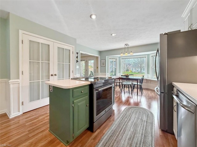 kitchen featuring light wood-style flooring, stainless steel appliances, light countertops, french doors, and green cabinets