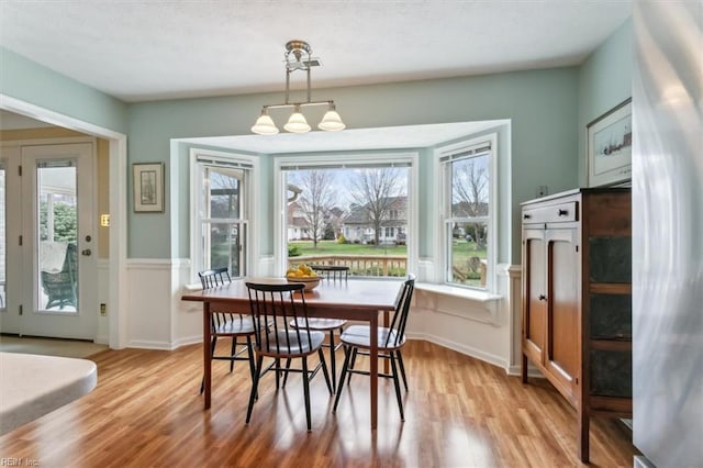 dining area with light wood finished floors, a notable chandelier, and baseboards