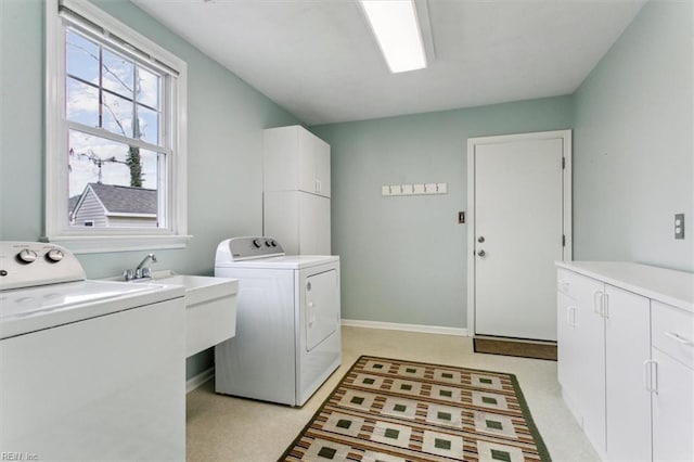 clothes washing area featuring washer and dryer, cabinet space, baseboards, and a sink