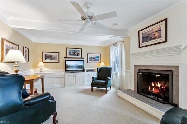 carpeted living area with beam ceiling, a lit fireplace, ceiling fan, and crown molding