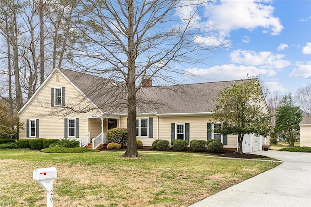 view of front of property featuring a garage, concrete driveway, and a front lawn