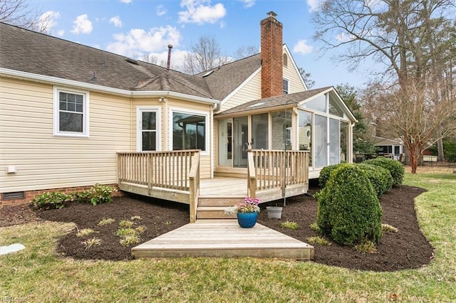 rear view of property featuring roof with shingles, a wooden deck, a sunroom, a chimney, and a lawn