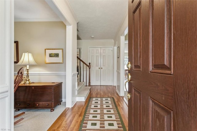 entryway featuring ornamental molding, a textured ceiling, wood finished floors, stairway, and baseboards