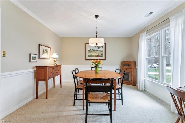 dining room featuring light carpet, visible vents, and ornamental molding