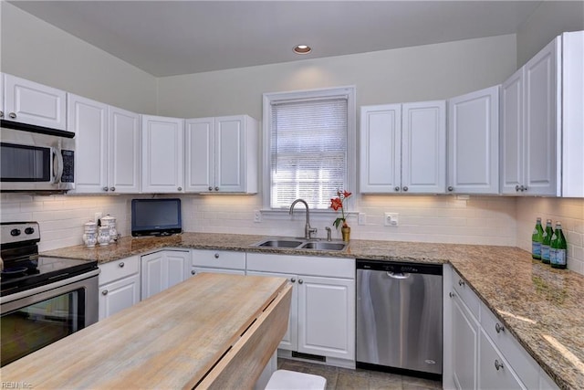 kitchen with a sink, tasteful backsplash, appliances with stainless steel finishes, and white cabinetry