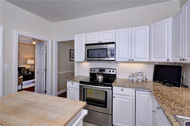 kitchen featuring backsplash, white cabinetry, stainless steel appliances, and light stone countertops