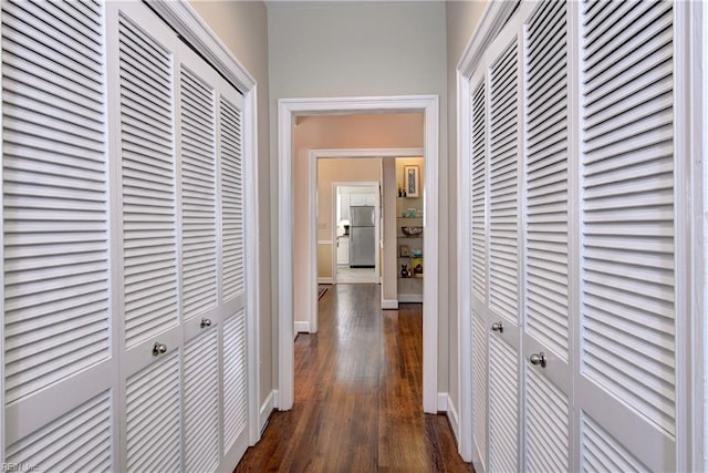 corridor with dark wood-type flooring and baseboards