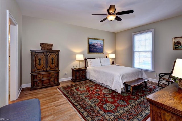 bedroom with light wood-style flooring, baseboards, and ceiling fan