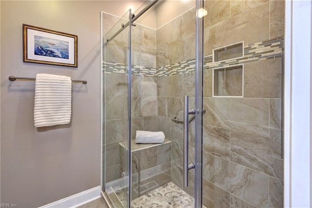 full bath featuring a shower stall and baseboards