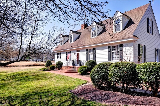 cape cod home with a chimney, roof with shingles, and a front yard