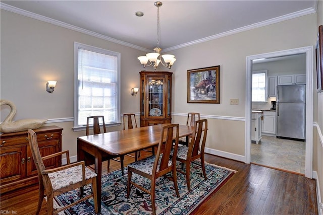 dining room featuring crown molding, a notable chandelier, dark wood-style floors, and baseboards