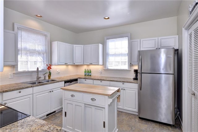 kitchen featuring a sink, butcher block countertops, white cabinets, appliances with stainless steel finishes, and backsplash