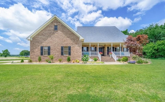 view of front of property featuring brick siding, covered porch, and a front yard