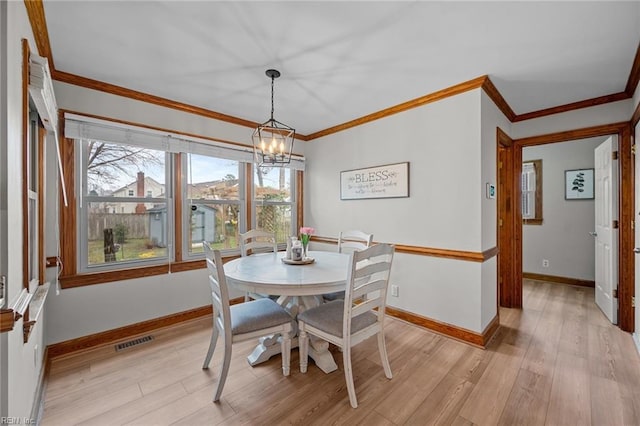 dining room featuring light wood finished floors, visible vents, baseboards, a chandelier, and ornamental molding