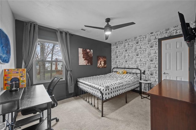 bedroom featuring visible vents, light carpet, wallpapered walls, ceiling fan, and an accent wall