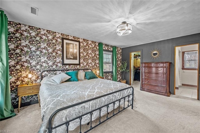 bedroom with a walk in closet, visible vents, a closet, carpet flooring, and wallpapered walls