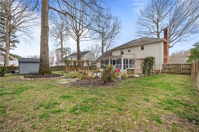 view of yard featuring a fenced backyard, a storage unit, an outdoor structure, and a sunroom