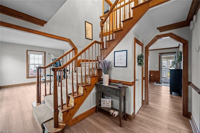 staircase featuring baseboards, wood finished floors, and ornamental molding