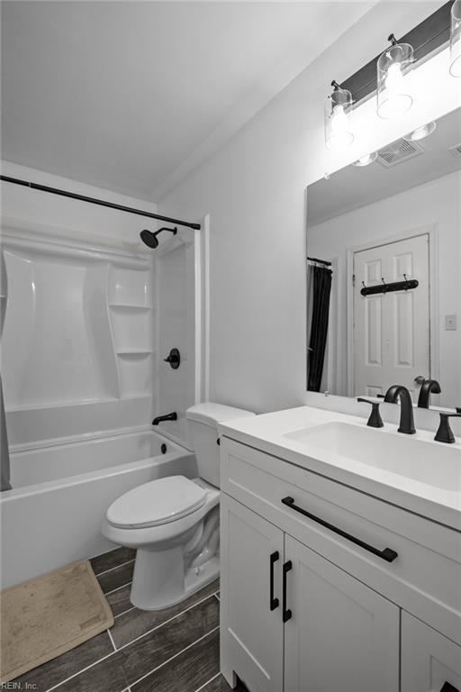 full bathroom with visible vents, wood finish floors, toilet, vanity, and shower / bathtub combination with curtain