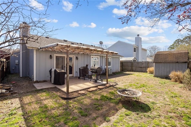 back of property with an outdoor fire pit, a storage shed, a fenced backyard, an outbuilding, and a patio