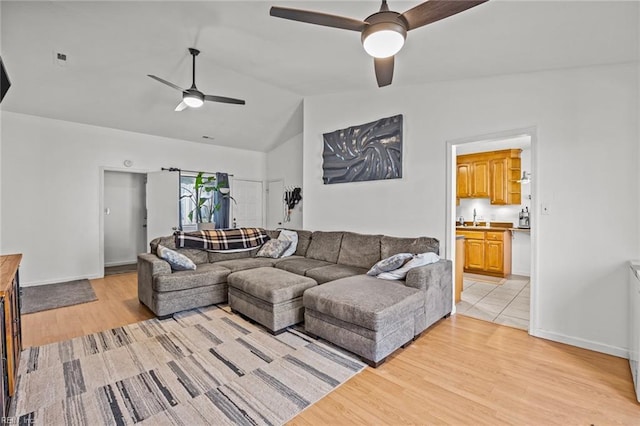 living room with light wood-type flooring, lofted ceiling, baseboards, and ceiling fan