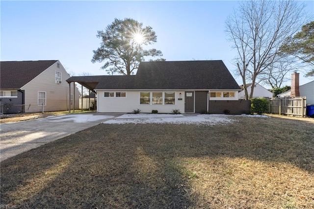 view of front of house with brick siding, concrete driveway, a front lawn, and fence