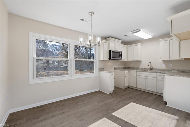 kitchen featuring stainless steel microwave, a sink, baseboards, and wood finished floors