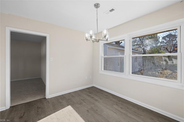 unfurnished dining area featuring a notable chandelier, visible vents, baseboards, and wood finished floors