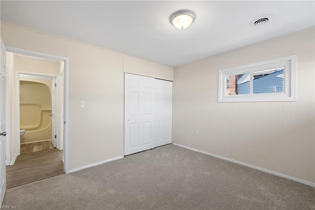 unfurnished bedroom featuring a closet, carpet flooring, baseboards, and visible vents