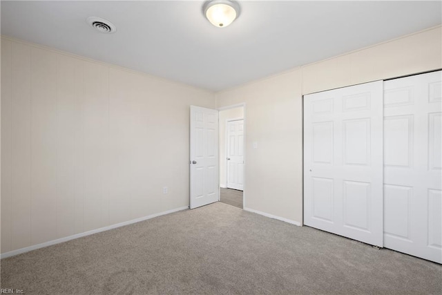 unfurnished bedroom featuring a closet, visible vents, baseboards, and carpet