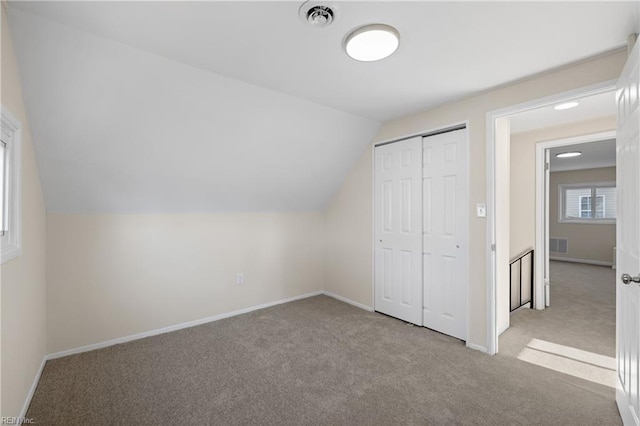 additional living space with lofted ceiling, baseboards, visible vents, and carpet floors