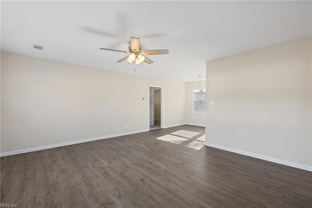 empty room with visible vents, ceiling fan with notable chandelier, dark wood-type flooring, and baseboards