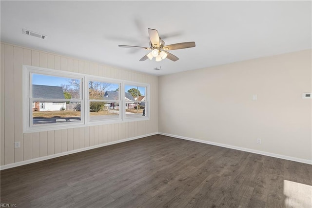 unfurnished room featuring a ceiling fan, baseboards, visible vents, and dark wood-style flooring