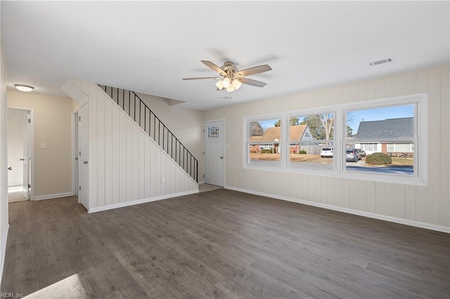 unfurnished living room with visible vents, baseboards, stairway, wood finished floors, and a ceiling fan