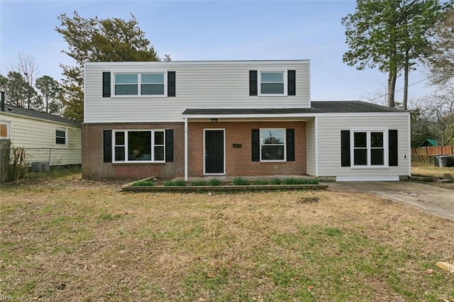 view of front of house with brick siding, a front lawn, and fence