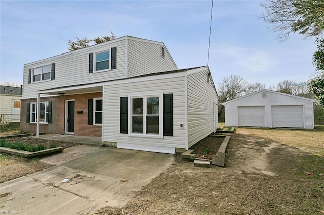 view of front of house featuring an outbuilding, a patio, brick siding, and a garage