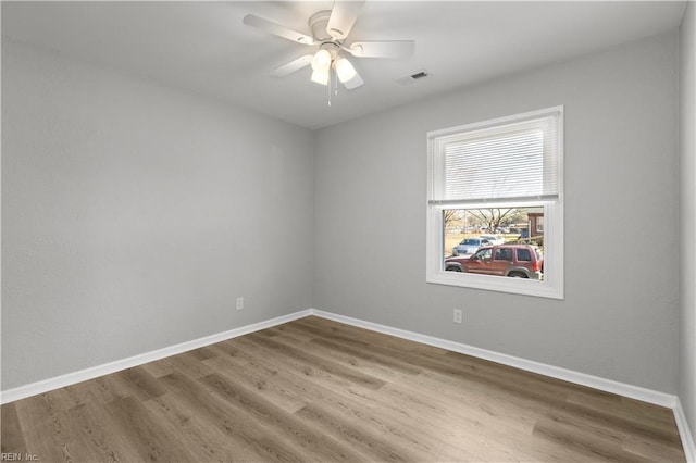 unfurnished room featuring a ceiling fan, wood finished floors, baseboards, and visible vents