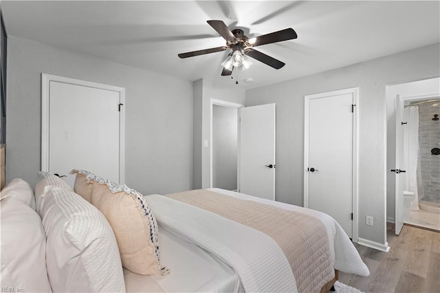 bedroom with connected bathroom, baseboards, light wood-type flooring, and a ceiling fan