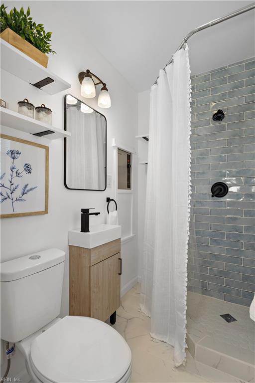 bathroom featuring toilet, marble finish floor, and a tile shower