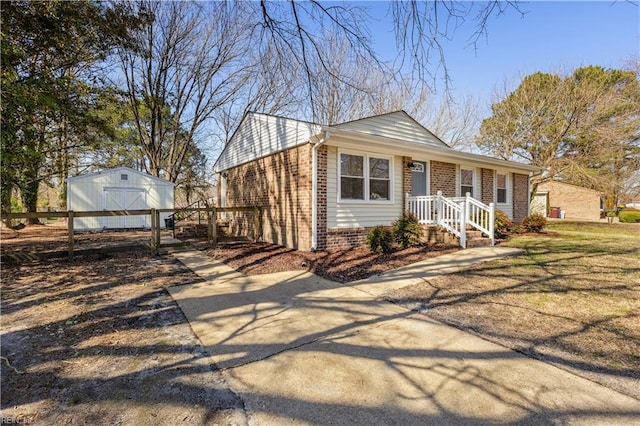 view of front of home with brick siding, a storage unit, an outbuilding, and fence