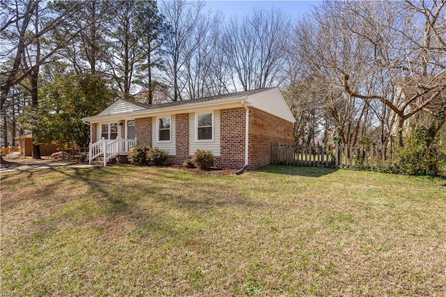 view of front of property featuring brick siding, a front lawn, and fence