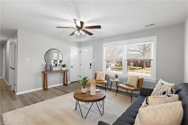 living area featuring ceiling fan, visible vents, baseboards, and wood finished floors