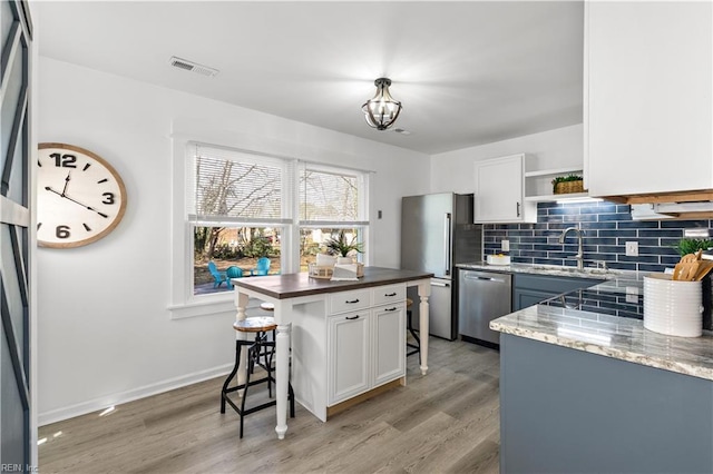 kitchen with visible vents, a breakfast bar, open shelves, stainless steel appliances, and decorative backsplash