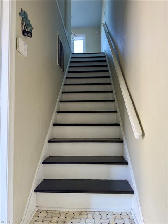 stairway featuring baseboards and visible vents