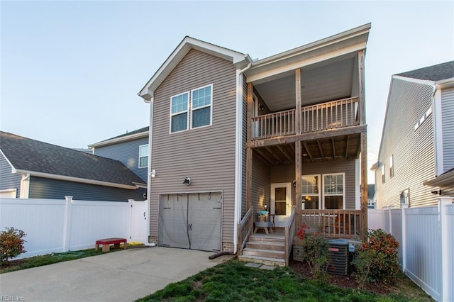 view of front of house with driveway, a porch, fence, a garage, and a balcony