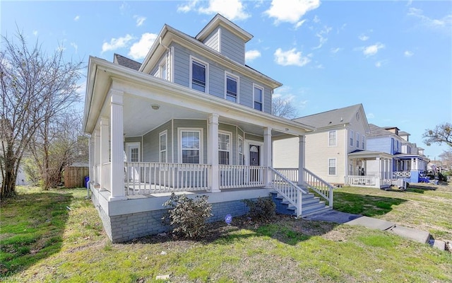 american foursquare style home featuring a porch and a front lawn